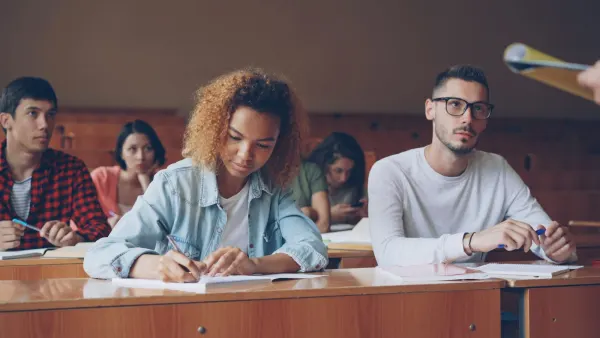 Students taking notes at their desks in a lecture hall.