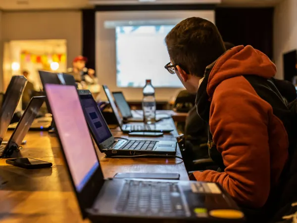 Students working on laptops at rows of desks in a computer room.